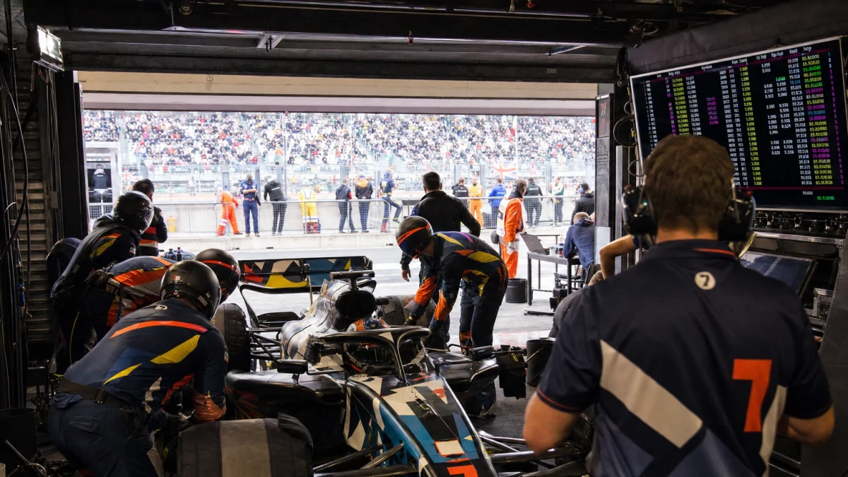 Formel 1-bilar i depågaraget under en kvalomgång med tidtavlan i bakgrunden.