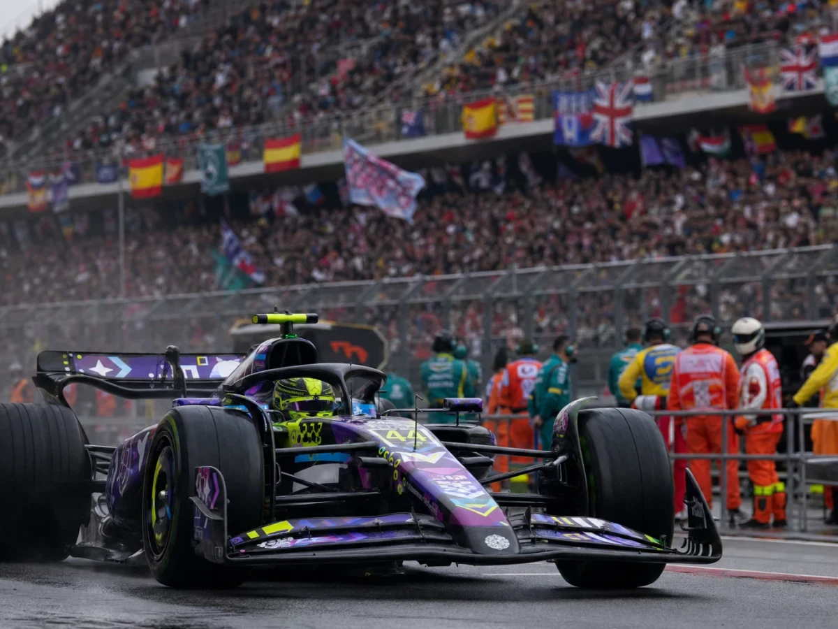 Röd formel 1-bil korsar mållinjen först framför fullsatta läktare på Circuit de Barcelona-Catalunya.
