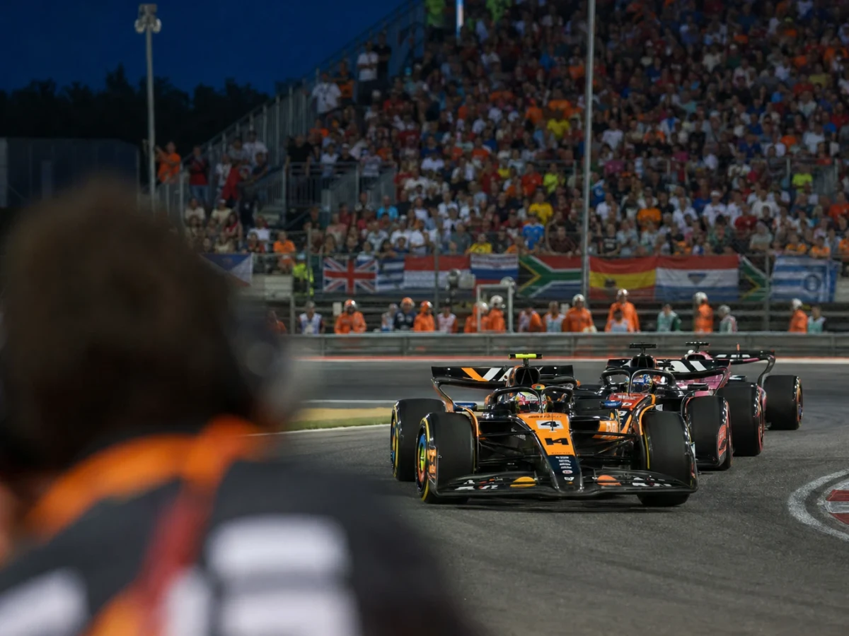 Röd formel 1-bil rullar ut ur depån under en morgonträning på en solig racerbana.