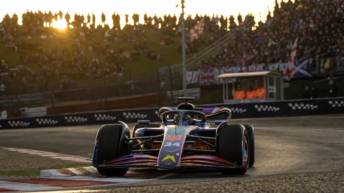 Förare och teknisk chef i samtal vid en mörkgrön formel 1-bil i depån inför en uppgradering.
