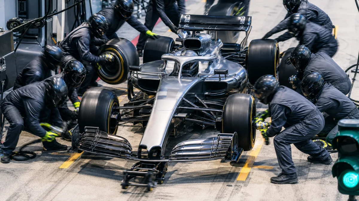 Formel 1-bil i depån med mekaniker runt om som byter alla fyra däcken samtidigt.